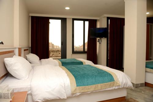 a bedroom with a large white bed with a window at Syros Hotel Erbil City Center in Erbil