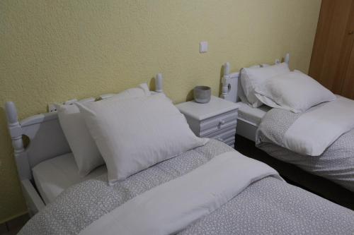 two beds with white pillows in a room at Dimos Suite in Arachova
