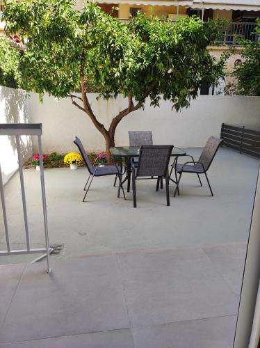 a patio with a table and chairs under a tree at Comfy Apartment in Nafplio