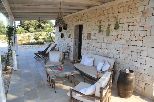 a patio with white chairs and a stone wall at TRULLI TERRA DI MEZZO in Cisternino