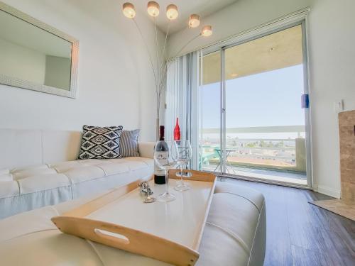 een woonkamer met een bank en een tafel met wijnglazen bij Hollywood Take 2! 1-Bedroom with Balcony & VIEWS! in Los Angeles