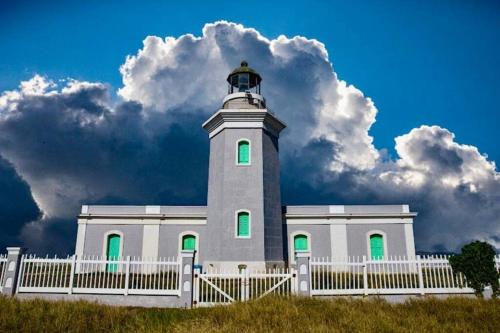 a lighthouse with a white fence in front of it at 2-BR Modern Oceanfront Apt Steps from Playa Sucia in Cabo Rojo