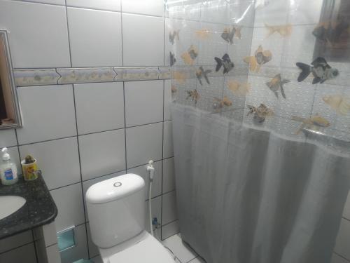 a bathroom with a toilet and a shower curtain at Casa de praia Tabatinga, sossego, sol e mar na Paraíba in Conde