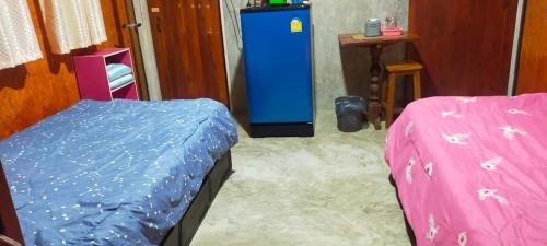 Cette chambre comprend deux lits et un réfrigérateur bleu. dans l'établissement เฮือนอุ้ยดี1, à Ban Khua Nam Chun