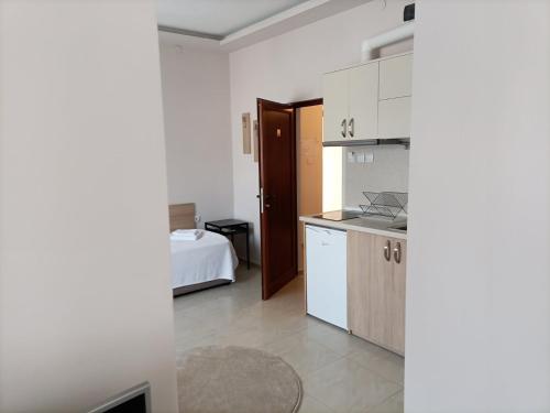 a kitchen with white cabinets and a bed in a room at Червената къща in Perushtitsa