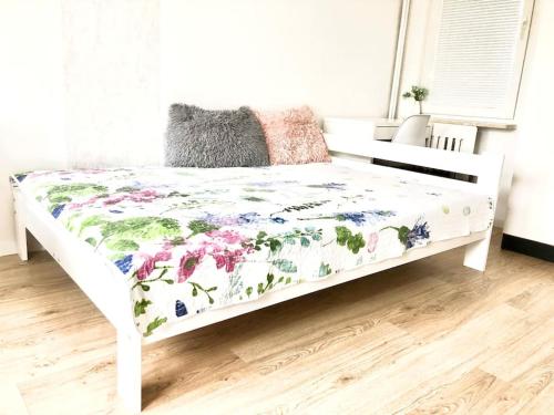 Una cama blanca con colcha floral. en przytulne mieszkanie, en Varsovia