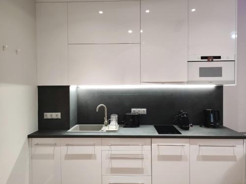 a kitchen with white cabinets and a sink at Spa Residence Carbona Mona Lila Apartman in Hévíz