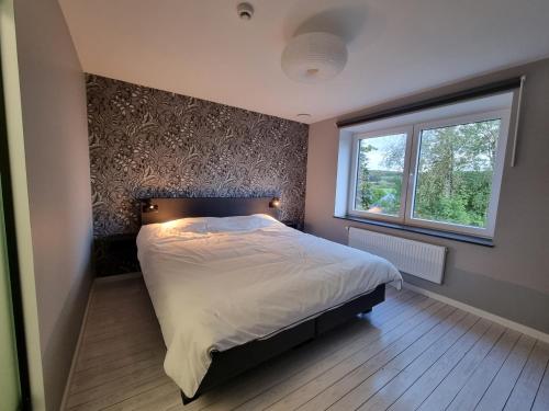 um quarto com uma cama grande e uma janela em Gîte 'Il y a' 11 à 13 pers #Nature #Familles #Calme #Pas d'abus d'alcool em Marche-en-Famenne