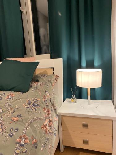 1 dormitorio con 1 cama y mesita de noche con lámpara en Airport Green Apartment KL21 - free parking, en Varsovia