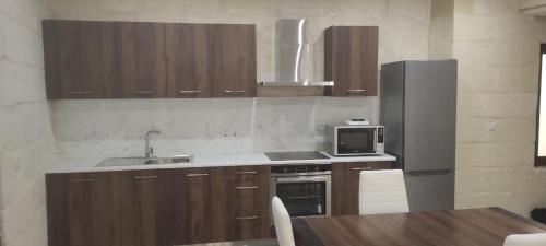 a kitchen with a sink and a refrigerator and a table at L-irdoss in Vittoriosa