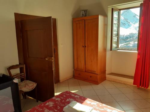 Cette chambre comprend une armoire, une fenêtre et une table. dans l'établissement appartement gentiane 4personnes dans gite "la maison d'augustin" classé 3 étoiles,la tour,73530 st jean d'arves, à Saint-Jean-dʼArves