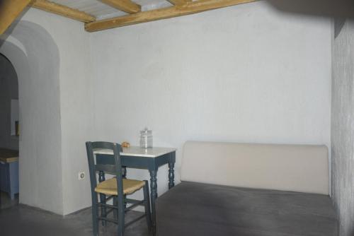 Avgonima Chios Spitakia Cottages في Avgonyma: طاولة وكرسي في غرفة بجدار أبيض