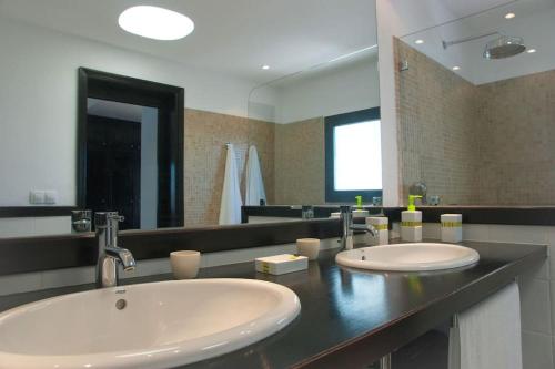 une salle de bains avec deux lavabos et un grand miroir dans l'établissement Casa Hugo, à Tías