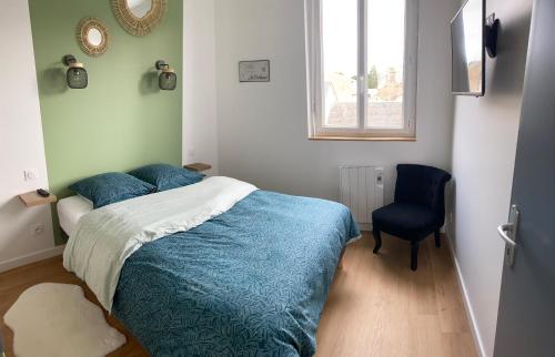 a bedroom with a bed with a blue comforter and a chair at Gîte mont-blan in Pontorson