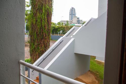 a white fence with a tree on the side of a building at Zenko Suave- 12 Madison West in Johannesburg