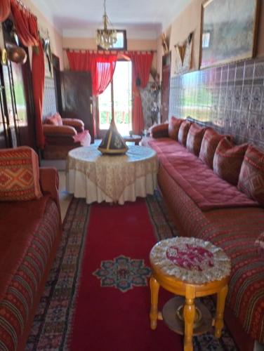 a living room with a red couch and a table at Villa de l'atlas in Tagadirt