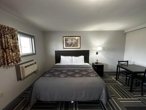 a hotel room with a bed and a table at Relax Inn - Saginaw in Saginaw