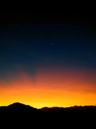 una puesta de sol sobre las montañas con la luna en el cielo en Chalé Ganesh - O chalé é maravilhoso!, en Cunha