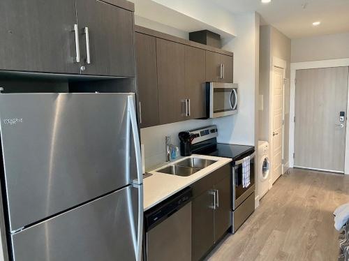 a kitchen with a stainless steel refrigerator and a sink at Lovely condo located close to downtown/waterfront! in Kelowna