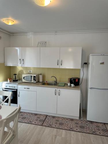 a kitchen with white cabinets and a white refrigerator at Fly Airport Residences & Therme-SELF CHECK-IN in Otopeni