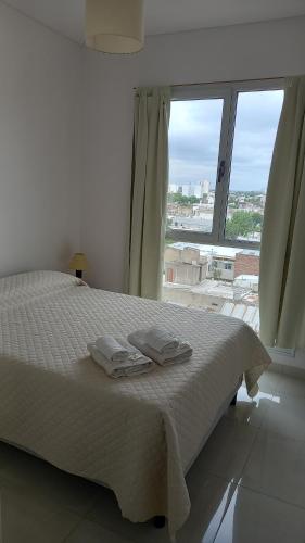 Schlafzimmer mit einem Bett mit weißer Bettwäsche und einem großen Fenster in der Unterkunft CENTRO NORTE ll a 400 mts del centro con cochera incluida in Bahía Blanca