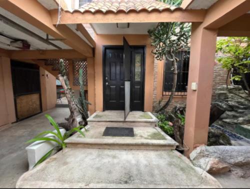 a house with a black door and a walkway at Casa Real Cozumel in Cozumel