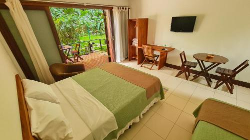 um quarto com uma cama e uma varanda com uma mesa e cadeiras em Canto dos Pássaros Suítes em Ubatuba