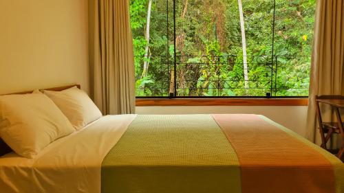 um quarto com uma cama e uma janela com vista em Canto dos Pássaros Suítes em Ubatuba
