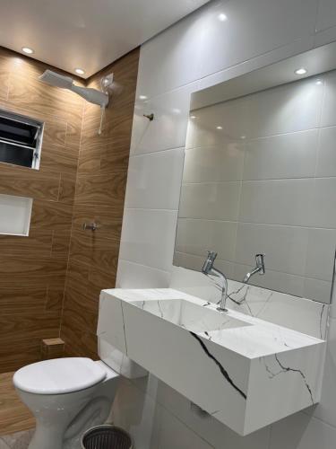 a white bathroom with a sink and a toilet at Hotel Ellos in Itaquaquecetuba