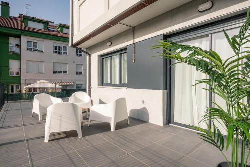 a patio with white chairs and tables on a balcony at El Prau de Mito in Cangas de Onís