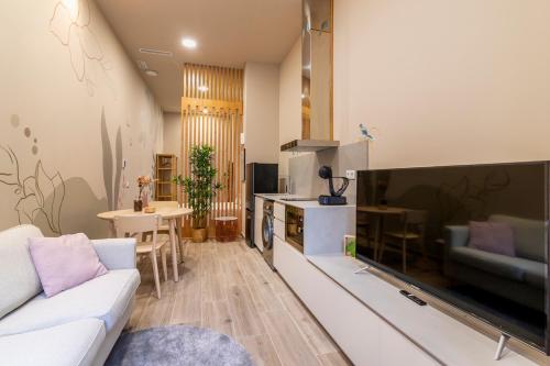 een woonkamer met een bank en een grote televisie bij Art Lofts Gardens in Valencia