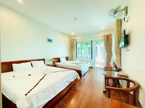 ein Hotelzimmer mit zwei Betten und einem Fernseher in der Unterkunft Phu Long Resort & Bar Phu Quoc in Phu Quoc