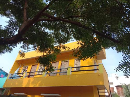 a yellow building with a balcony in front of it at Thendralhomestay in Puducherry
