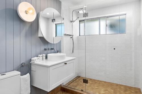 a white bathroom with a sink and a shower at Jacaranda Noosa in Noosa Heads