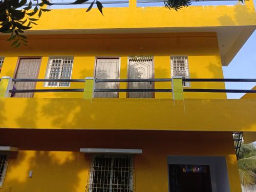 a yellow building with windows and a balcony at Thendralhomestay in Puducherry
