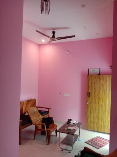 a living room with pink walls and a couch and a table at Thendralhomestay in Puducherry