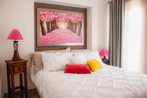 a bedroom with a white bed with two red and yellow pillows at Luxury Suite, Bellas Villas, Villa LUNA in San Miguel de Allende