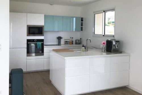 a white kitchen with a sink and a microwave at Odyssée de Quiberville - Villa vue mer d'exception in Quiberville