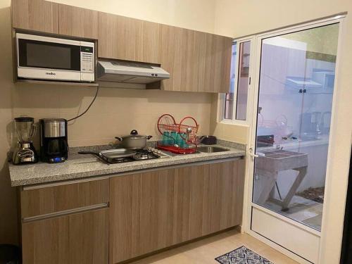 a small kitchen with a microwave and a stove at Paradisiaca casa con Laguna y Alberca in Veracruz