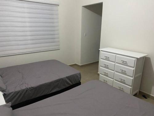 a bedroom with two beds and a dresser and a window at Paradisiaca casa con Laguna y Alberca in Veracruz
