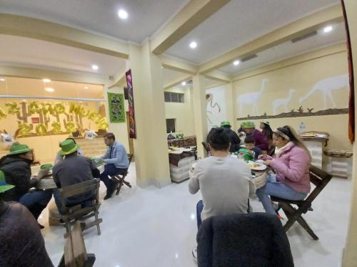 een groep mensen die aan tafel zitten en groene hoeden dragen bij Hotel REY DAVID in Uyuni