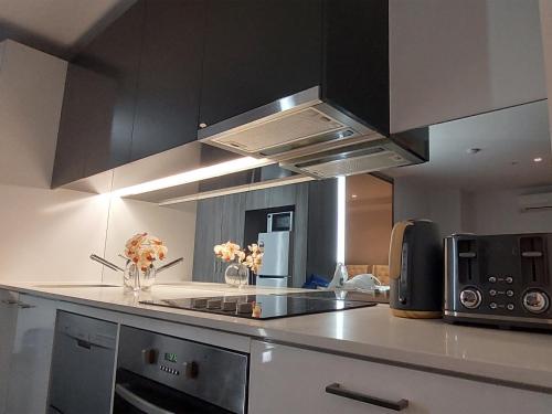a kitchen with black cabinets and a stove top oven at CBD Modern 2B2B Apt, Indoor Pool Sauna, Nice view in Melbourne