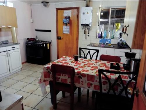 cocina con mesa y mantel rojo y blanco en Refugio Martin Pescador, en Coyhaique