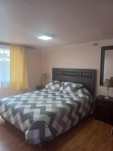 - une chambre avec un lit et une couverture en damier dans l'établissement Refugio Martin Pescador, à Coyhaique