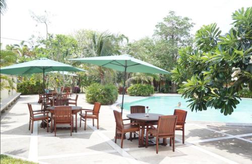 a group of tables and chairs with umbrellas next to a pool at Sea sand sun Condominiums in Rayong