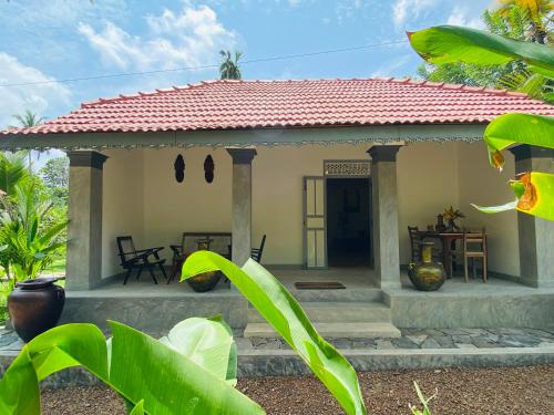a small white house with a red roof at Birdsong Villa in Rathgama