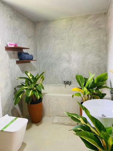 a bathroom with a tub and a sink and two plants at Birdsong Villa in Rathgama