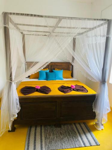 a bedroom with a canopy bed with blue pillows at Birdsong Villa in Rathgama