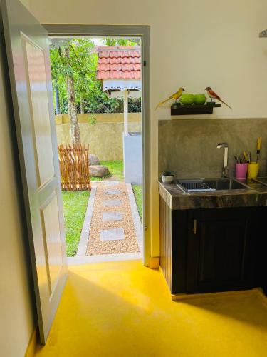 a kitchen with a door open to a yard at Birdsong Villa in Rathgama