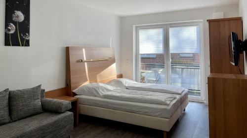 a bed in a room with a window and a couch at Stilvoll Wohnen in Oldenburg Kreyenbrück Apartments in Oldenburg